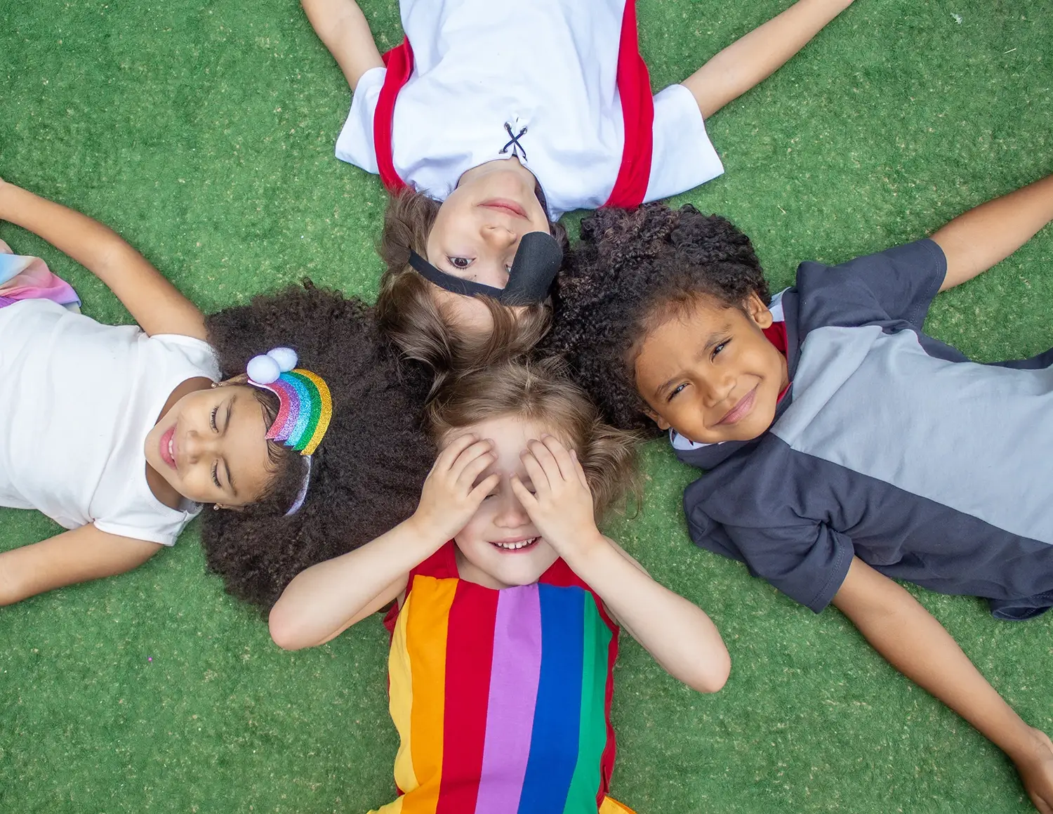Quatro crianças deitas na grama, fantasiadas - Just Real Moms