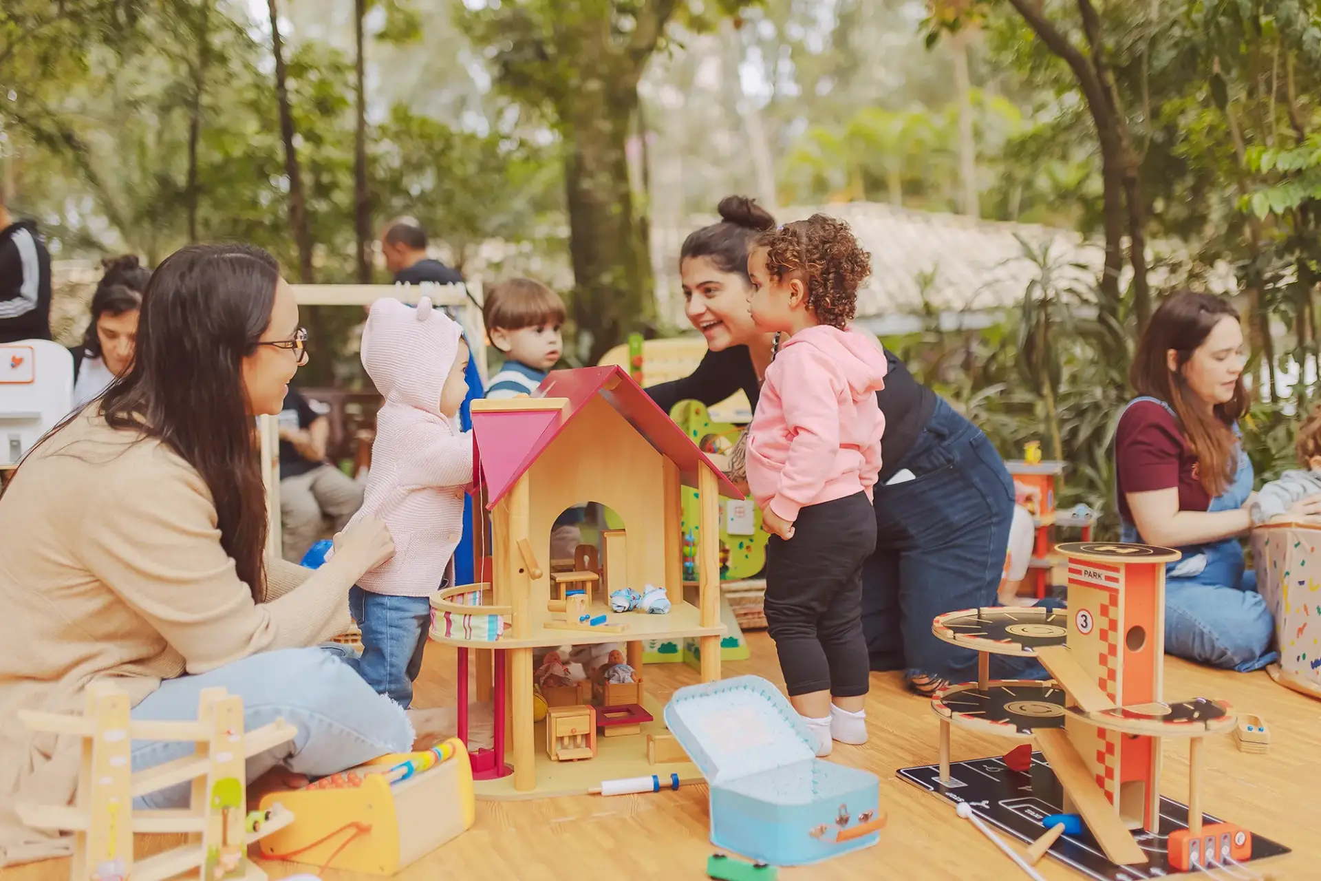 Mães e crianças brincando em festa infantil com brinquedos educativos da Bolimbolá