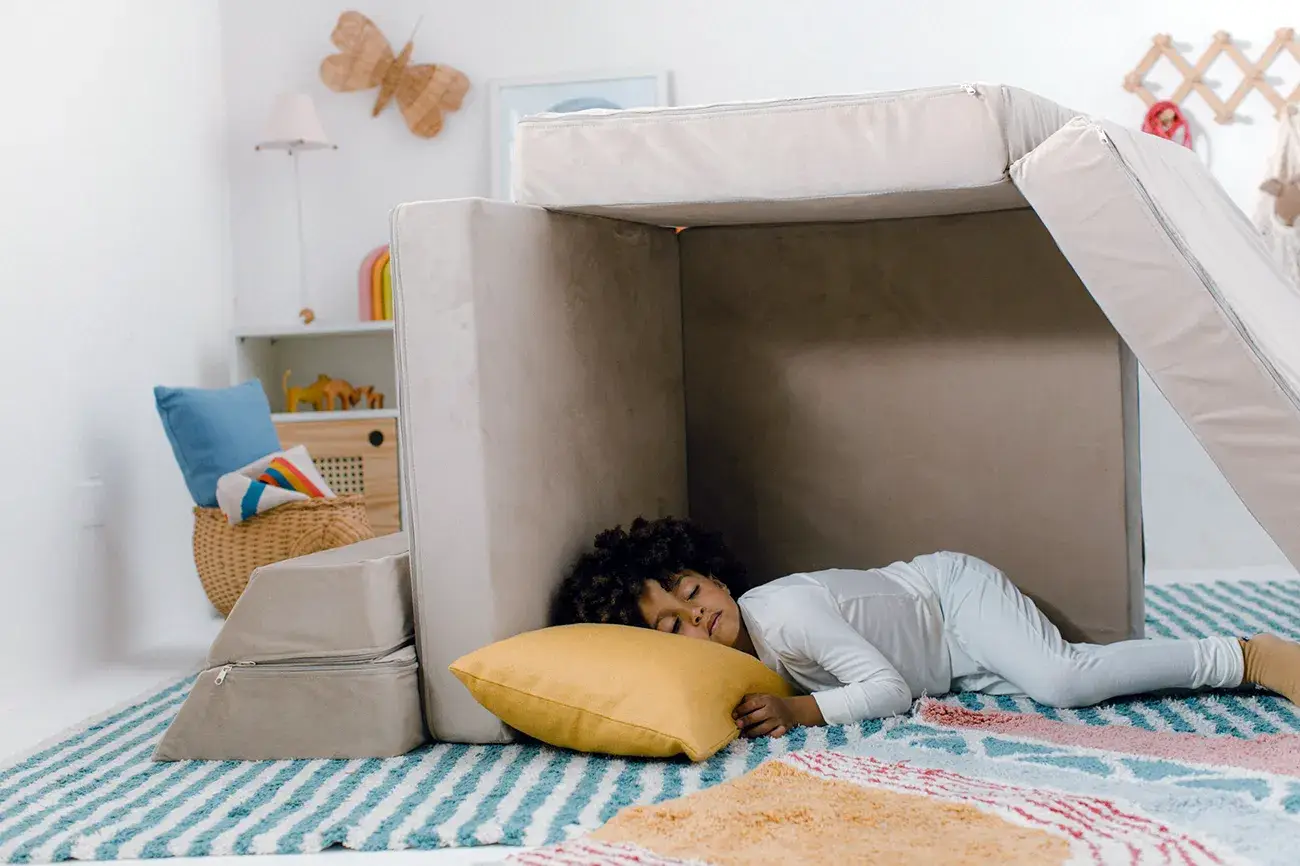 Menino pequeno dormindo embaixo do sofá modular da Five Little Monkeys