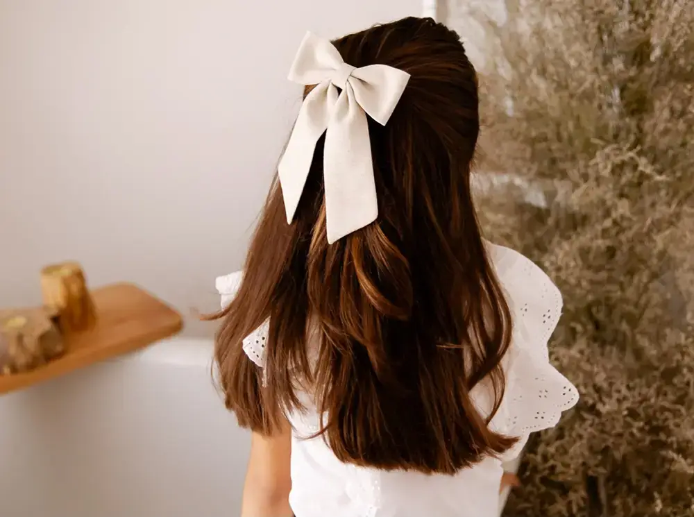 Menina com laço infantil de cetim branco da Lacos Blush