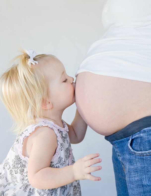 Little Girl Kissing New Sibling to Be