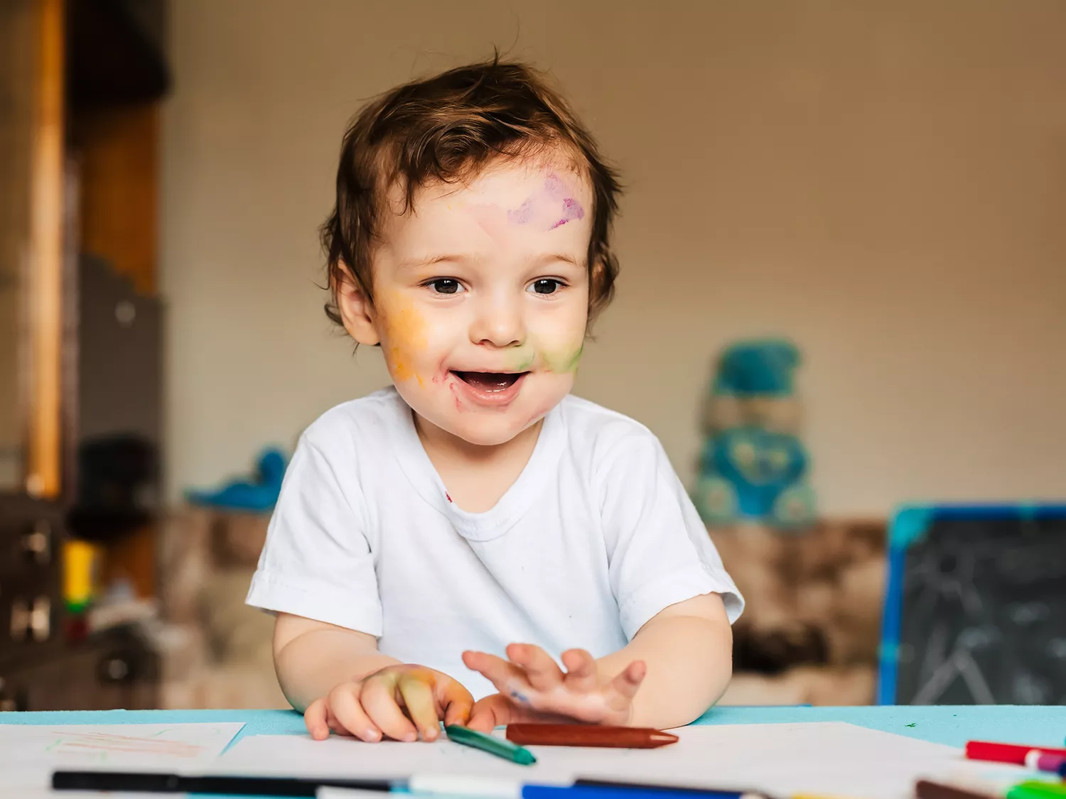Menino brincando de desenhar em mesa com gis colorido
