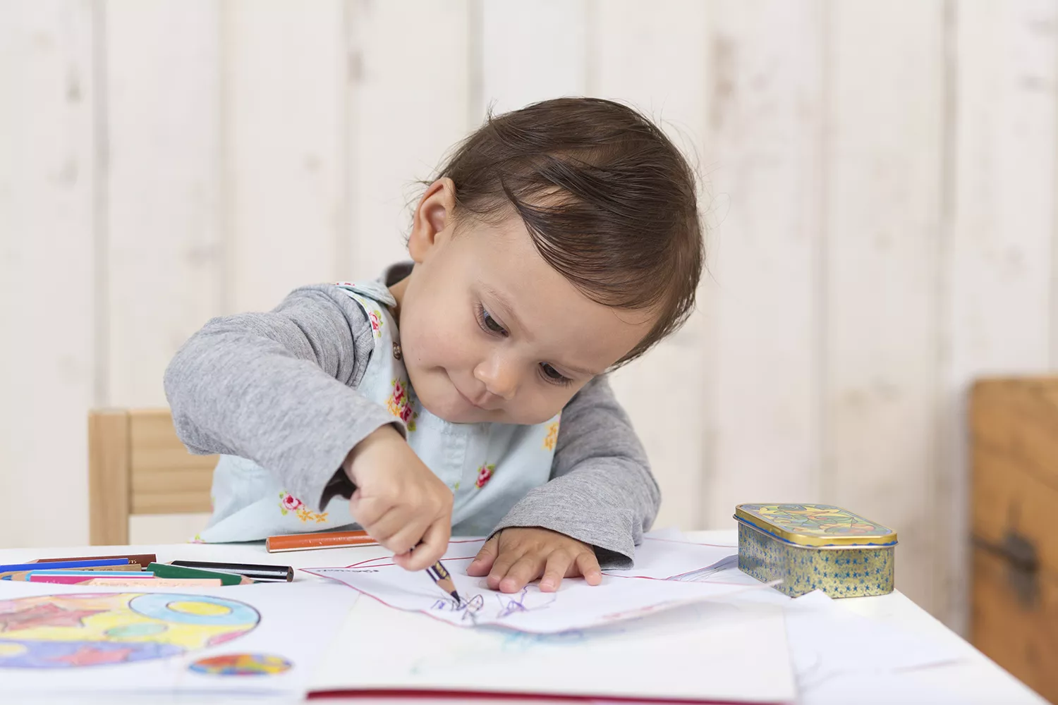 Menina bebê sentada em mesa infantil desenhando e sorrido