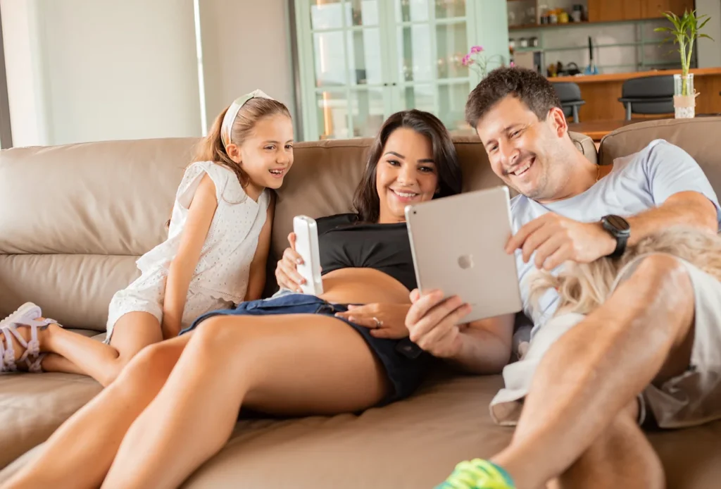 Família no sofá vendo o ultrassom portável do bebê