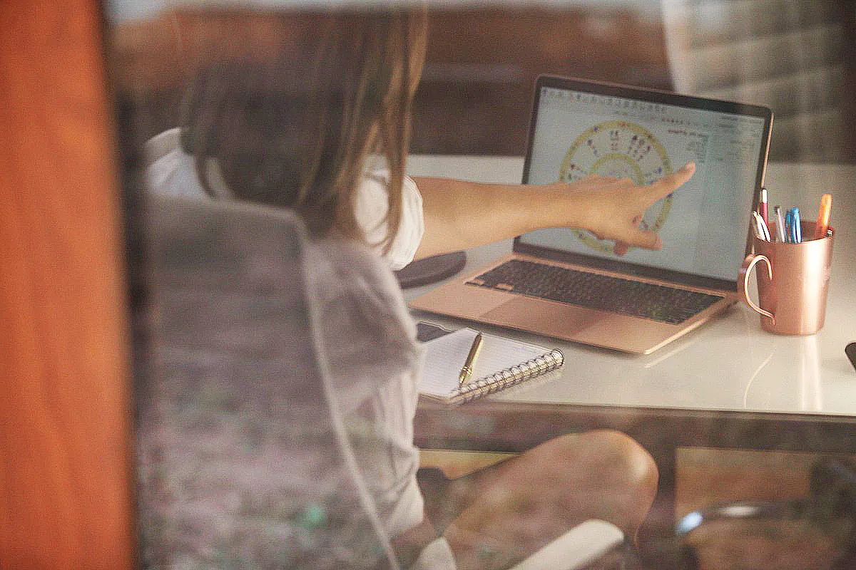 Mulher sentada de frente para um computador com um Mapa Astral Infantil