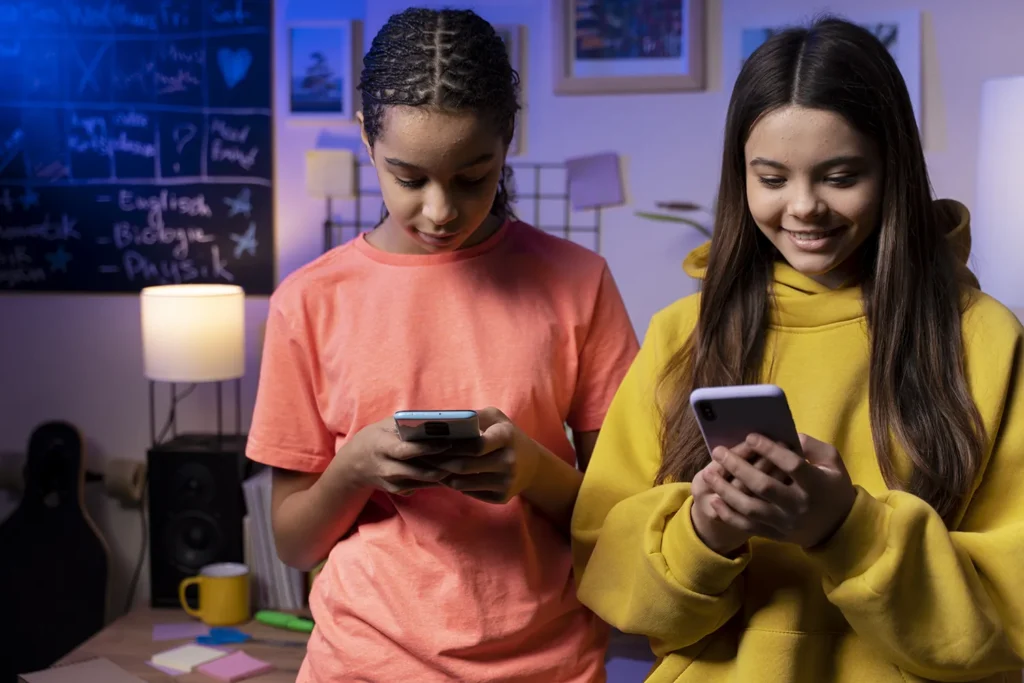 duas meninas adolescentes em um quarto com seus smartphones na mão