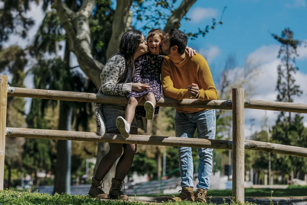 Pais beijando filha na bochecha - Férias escolares de julho