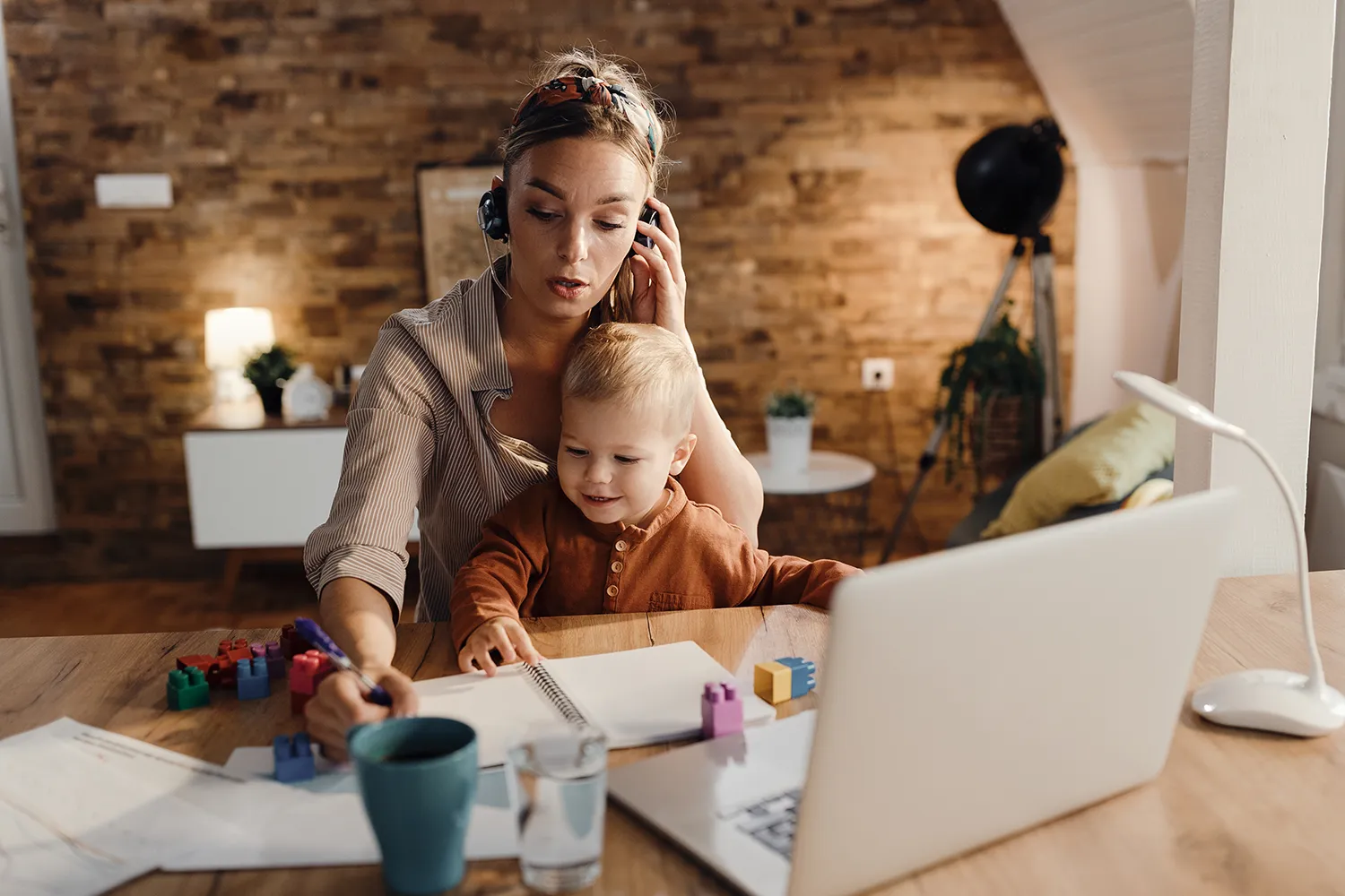 Mãe com bebê no colo enquanto trabalha - 7 ideias de negócios online para mães que querem trabalhar de casa