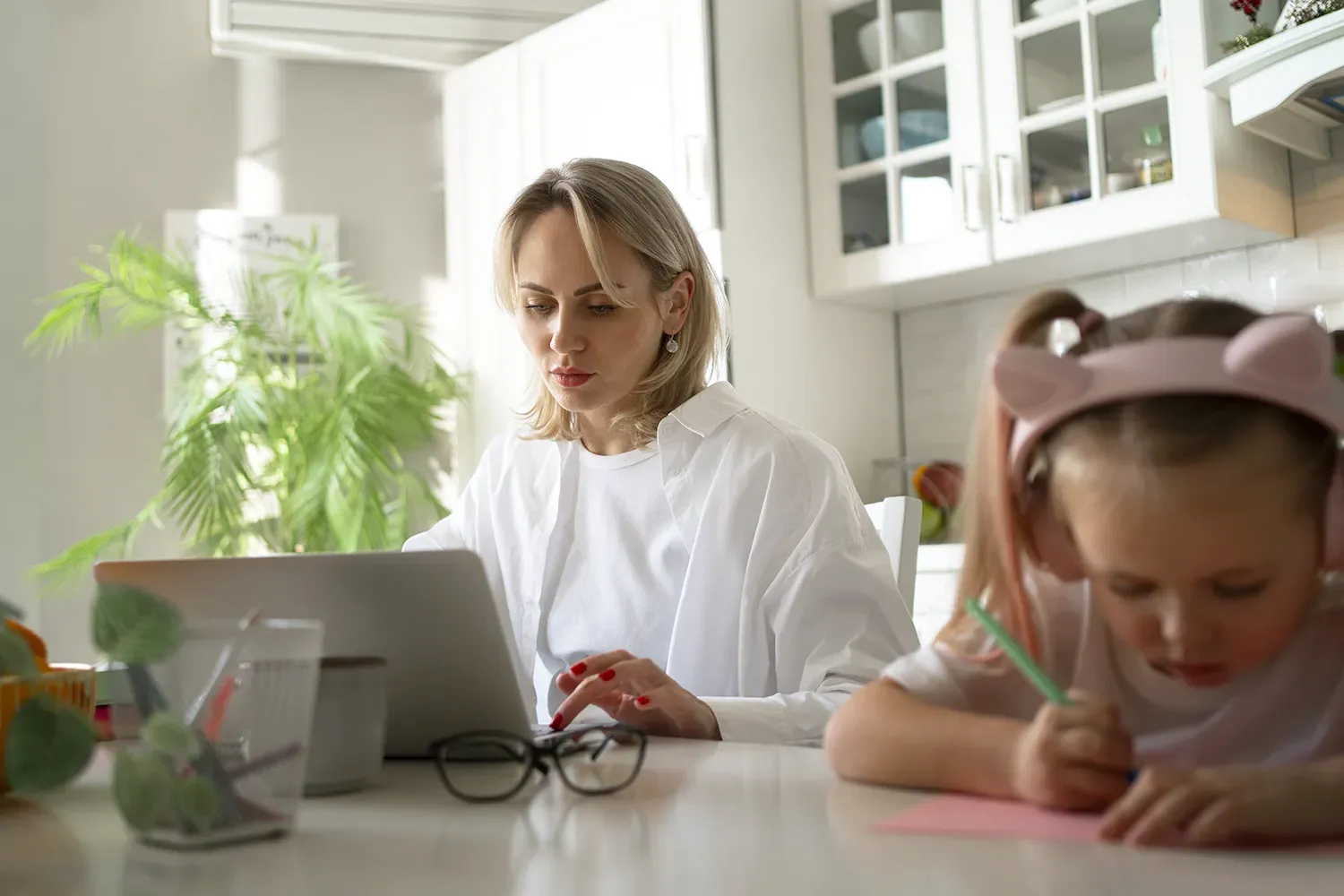 mãe empreendedora trabalhando de casa com a filha ao lado - maternidade muda a carreira