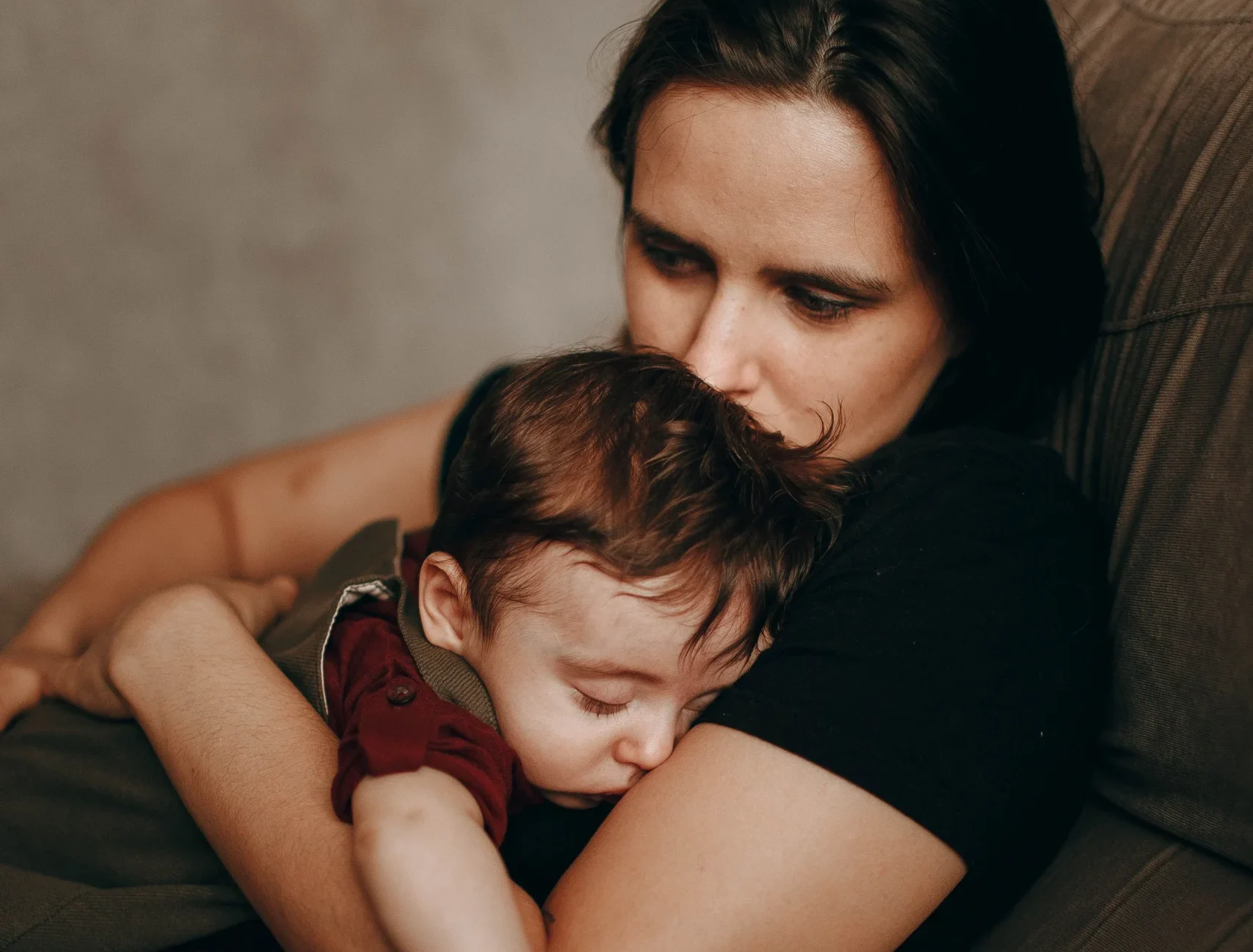 Mãe jovem segurando filho no colo visivelmente abalada pelo esgotamento e solidão na maternidade