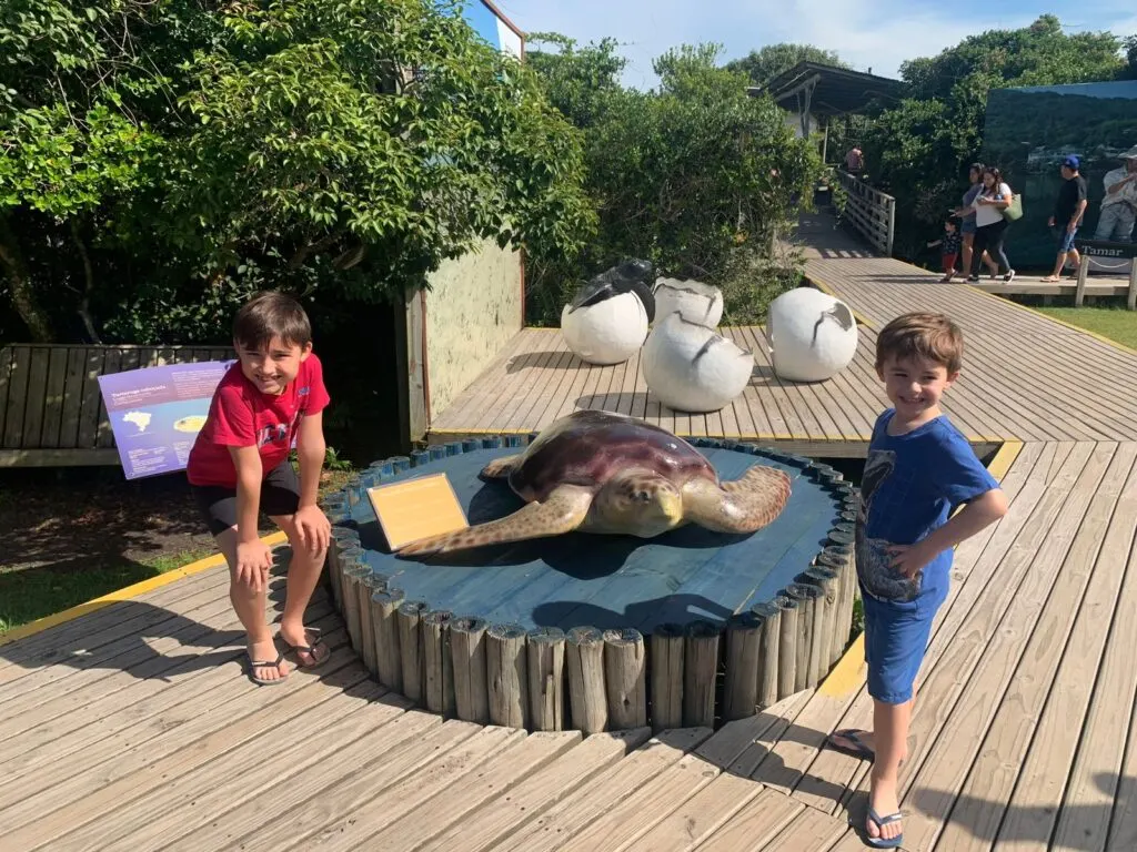 Crianças com escultura de tartaruga em deck na cidade de Florianópolis (SC)
