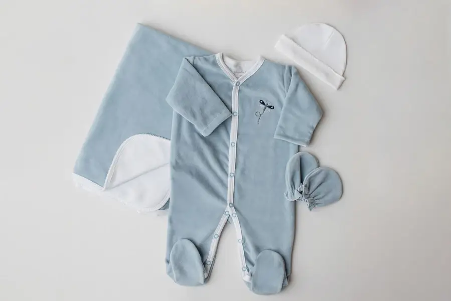 Pijama infantil de plush azul com acessórios ao lado - lacinho, gorro e luva - Just Real Moms