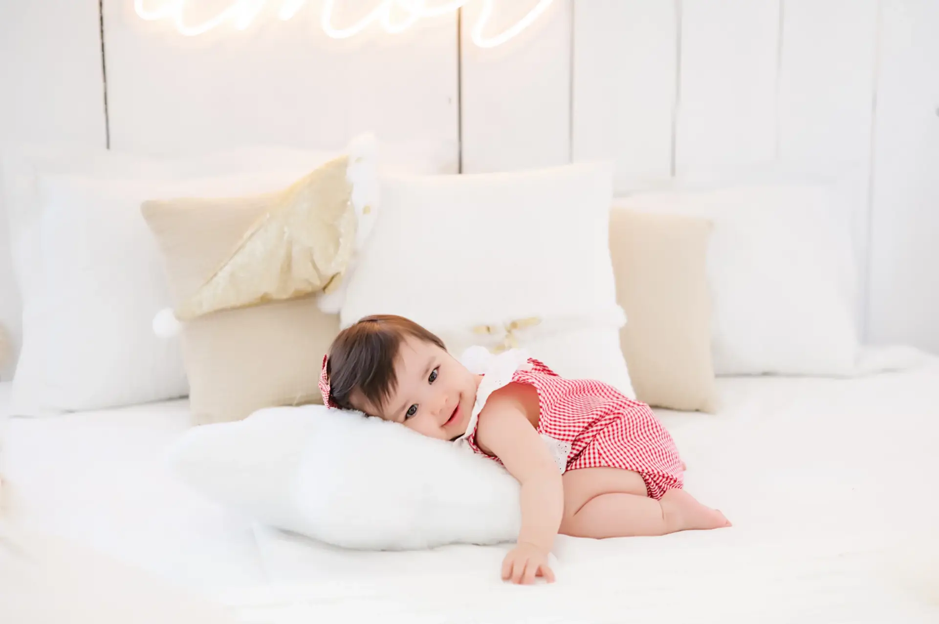 Menina vestindo macacão xadrez vermelho e branco deitada na cama - Just Real Moms