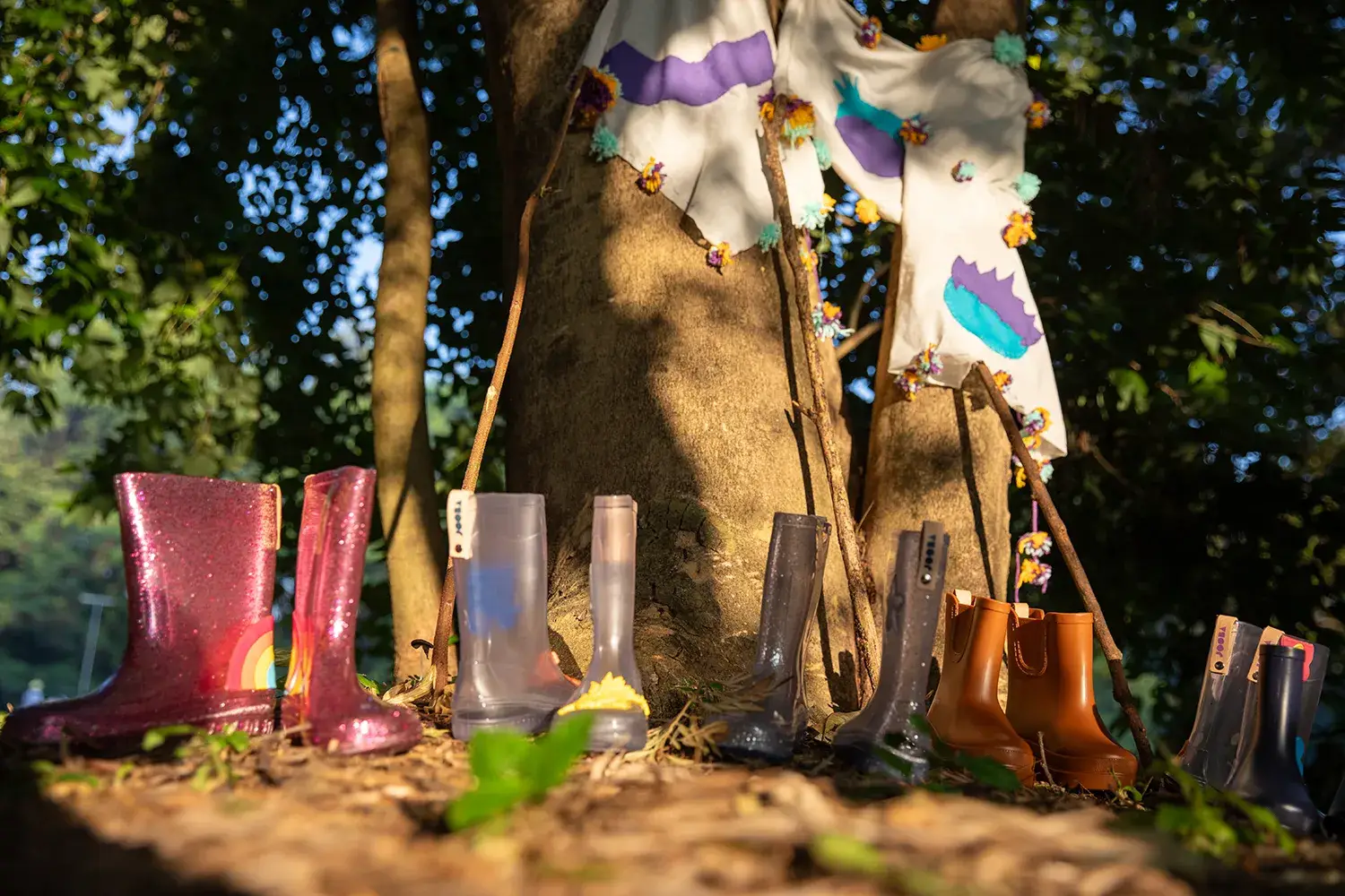 Galochas infantis ao lado de duas árvores em campanha da marca infantil Jooba