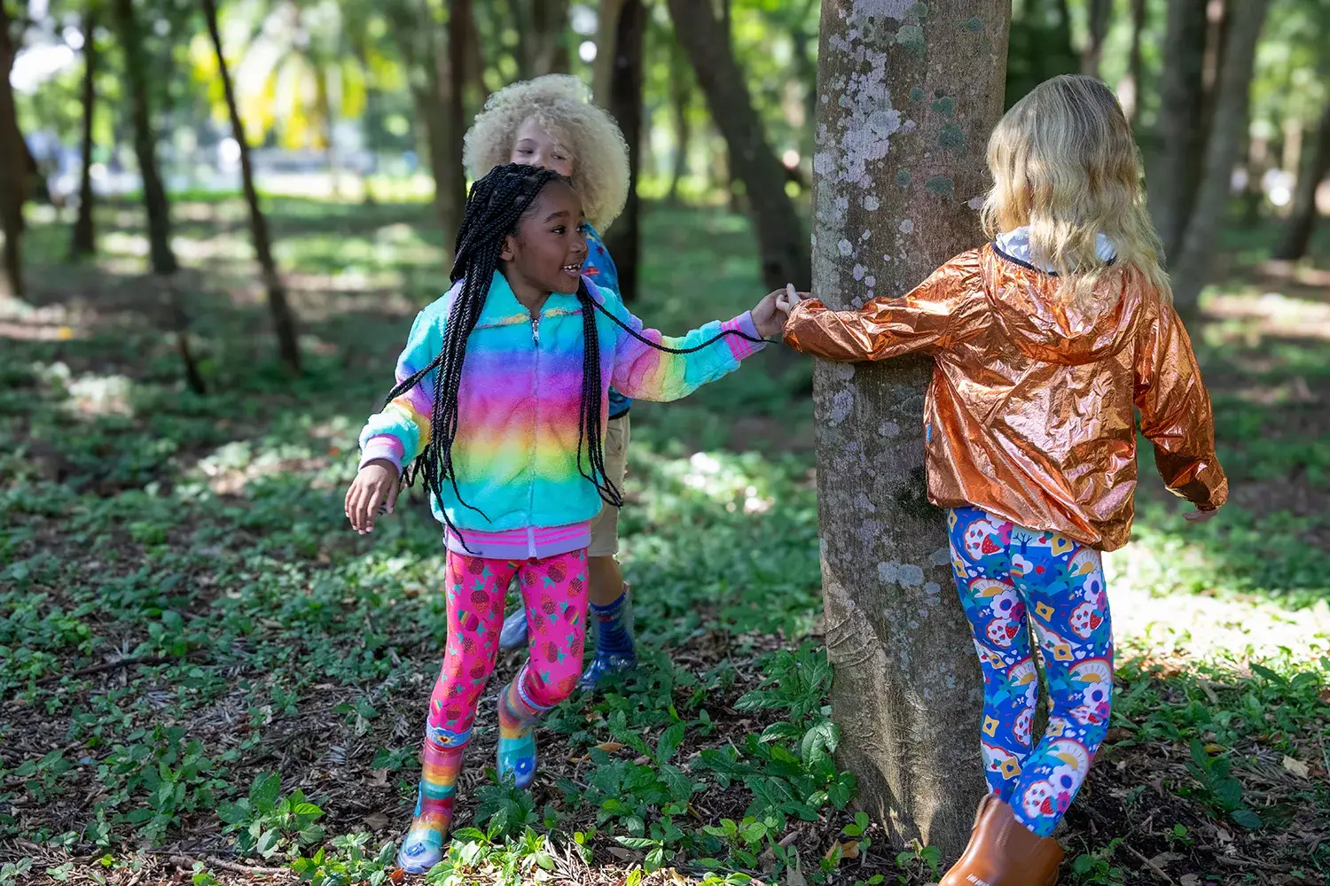 Crianças brincando em volta de uma árvore em campanha da marca infantil Jooba