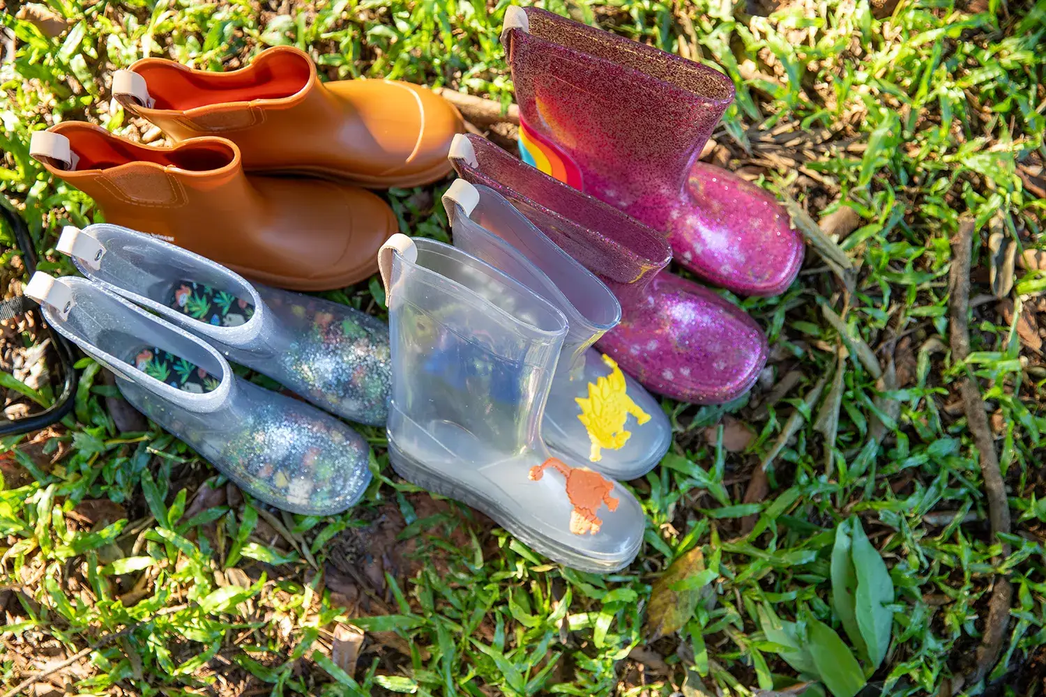 Quatro galochas infantil em um gramado em campanha da marca infantil Jooba