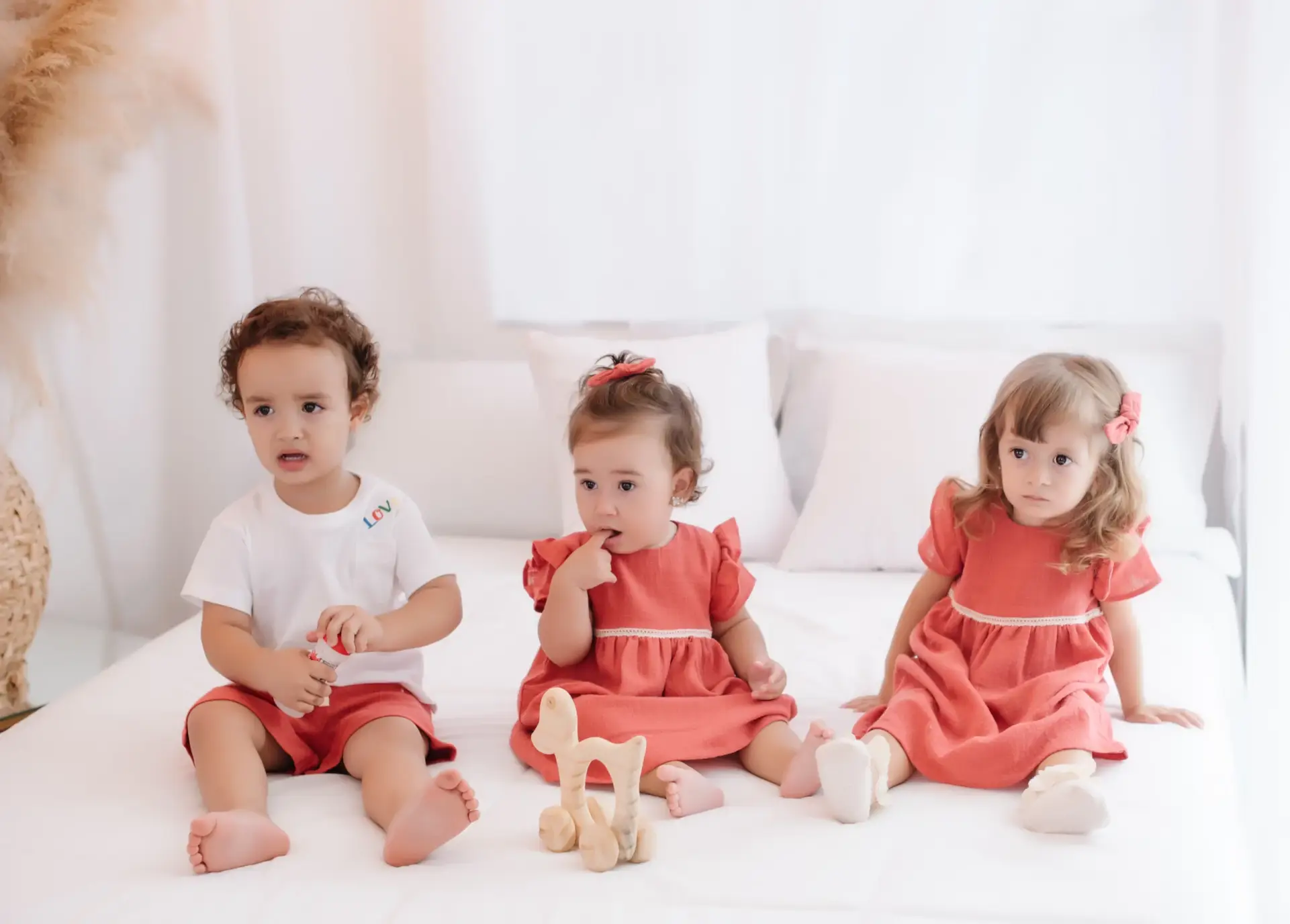 Três crianças sentadas na cama vestindo Mini Amati - Just Real Moms